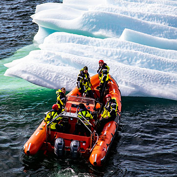 En gummibåd er i gang med at flytte et isbjerg, der er ved at flyde ind i Fregatten Niels Juel. Niels Juel var i juni 2020 i Grønland for at operere under Arktisk Kommando og bidrage til suverænitetshævdelsen og overvågning af farvandet.